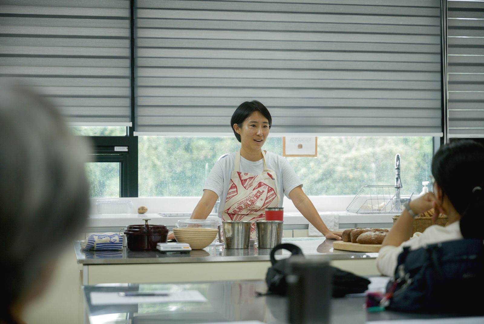 Cooking instructor explaining a recipe to students in a bright kitchen