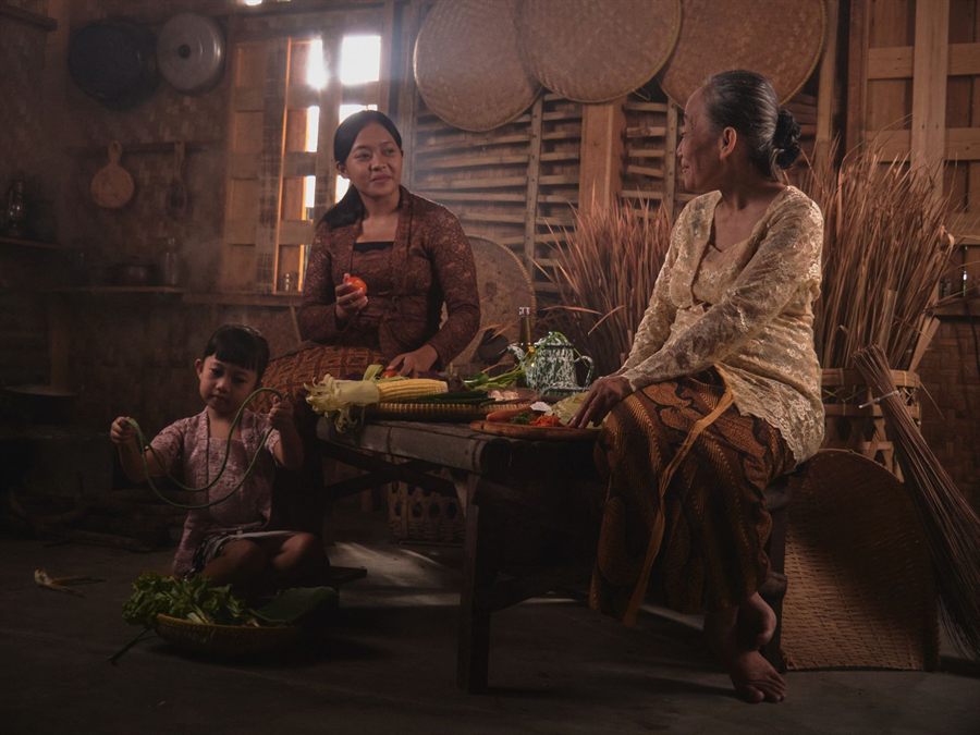 Family preparing traditional food together in a rustic Indonesian kitchen