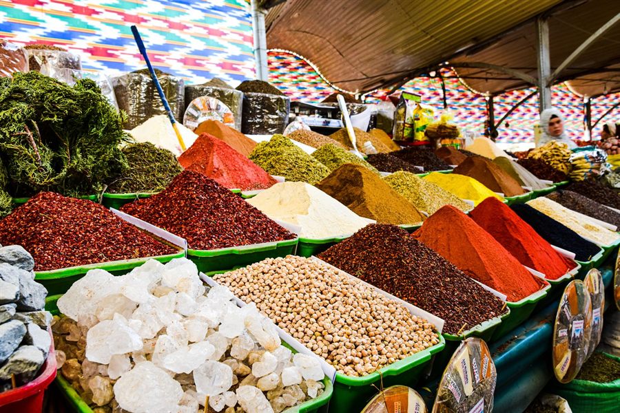 Heaps of colorful spices for sale under awnings at a bazaar